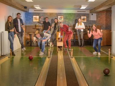 Gruppe von Menschen spielt Kegeln in einer gemütlichen Indoor-Kegelbahn.