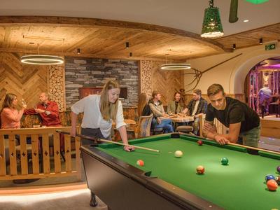 Menschen spielen Billard und entspannen in einer gemütlichen Lounge mit Holzvertäfelung.
