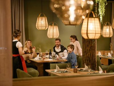 Gäste sitzen an einem Tisch im Restaurant, während eine Kellnerin ihnen das Menü bringt.