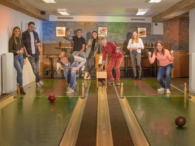 Gruppe von Menschen spielt Kegeln in einer gemütlichen Indoor-Kegelbahn.