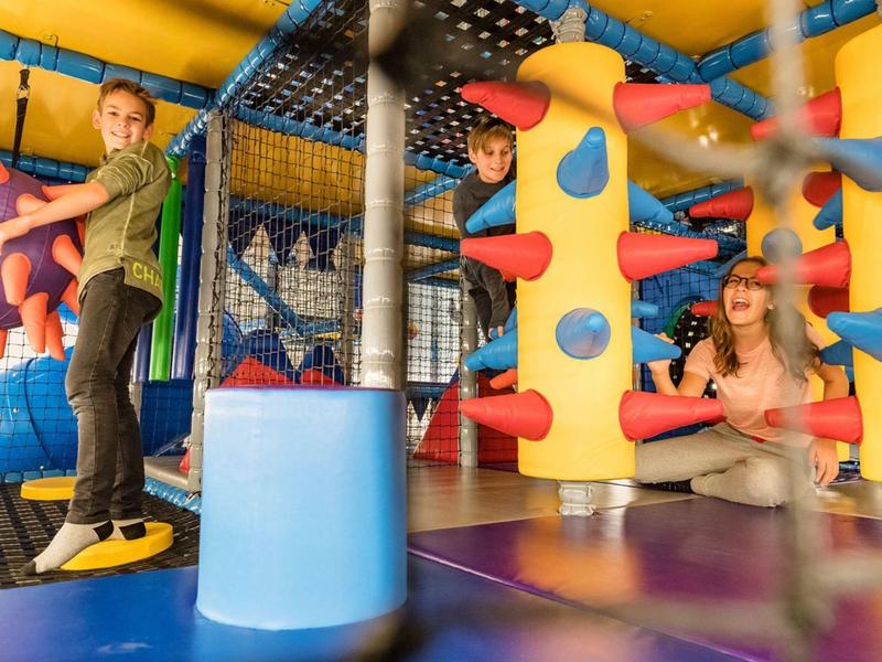 Kinder spielen und klettern in einer farbenfrohen Indoor-Spielplatzanlage.