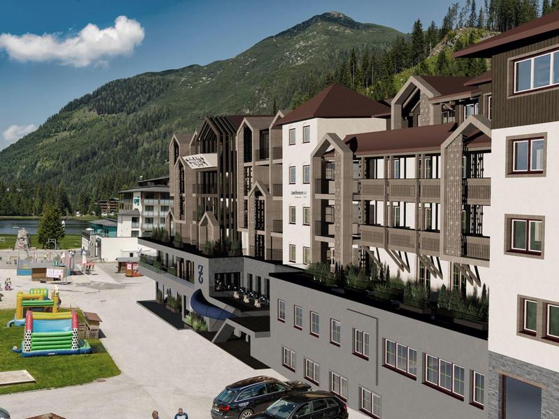 Großes Hotelgebäude in Berglandschaft mit Spielplatz und Parkplätzen