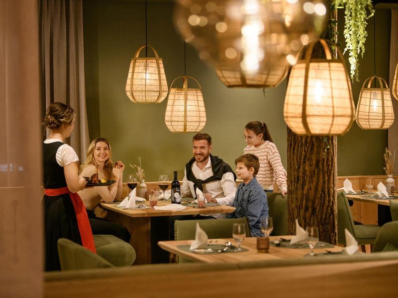 Gäste genießen in einem gemütlichen Restaurant bei warmem Licht ihr Essen.