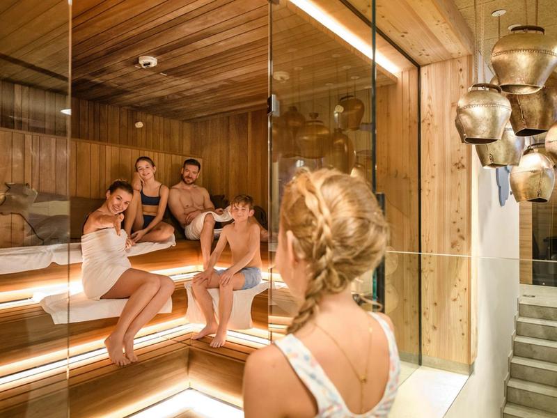 Menschen entspannen in einer modernen Sauna mit Holzauskleidung und Glaswänden.