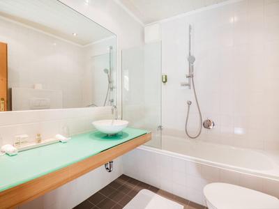 Helles Badezimmer mit Dusche, Badewanne und Waschbecken auf Holztheke unter großem Spiegel.