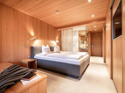 Modernes Hotelzimmer mit Holzverkleidung, gemütlichem Bett und integriertem Badezimmer.