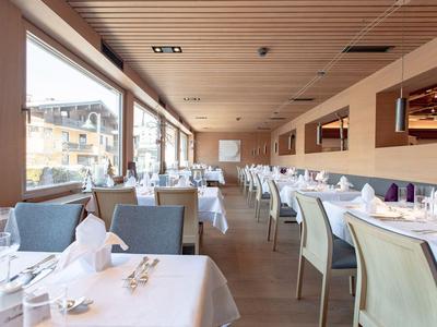 Světla restaurace s bílými ubrusy a velkými okny s výhledem na město.