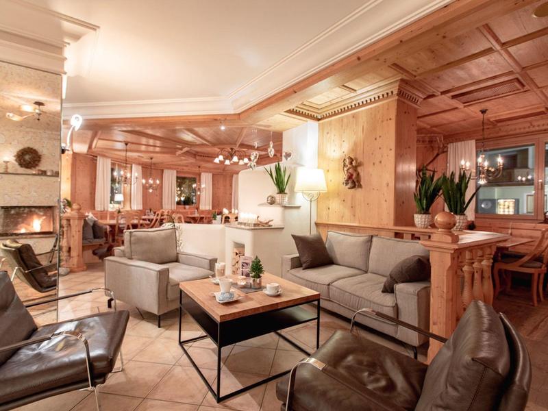 Gemütlicher Hotel-Lounge-Bereich mit Sofas, Sesseln, Kamin und warmem Holzdekor.