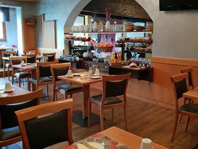 Przytulna jadalnia z drewnianymi stołami i krzesłami w ciepłych kolorach oraz kwiatowymi dekoracjami.