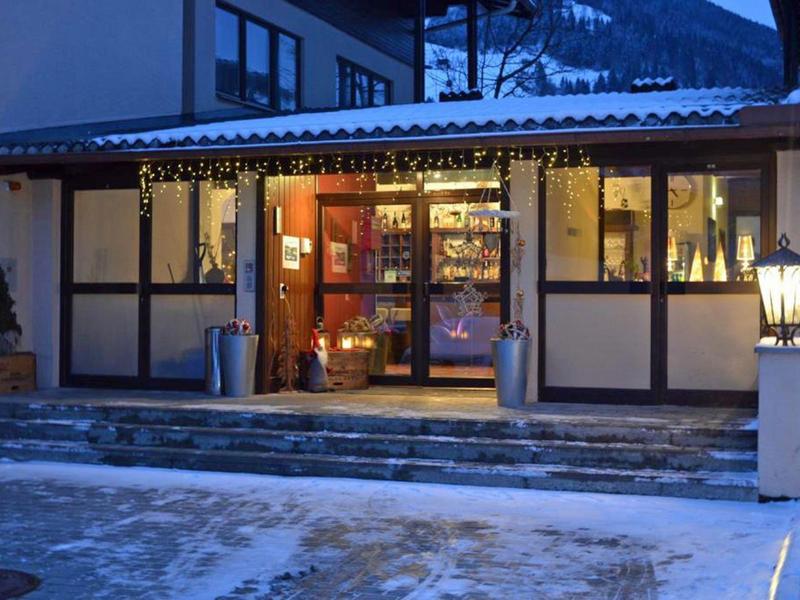 Eingang eines Hotels in den Abendstunden mit Schneebedecktem Boden und warm beleuchtetem Innenbereich.