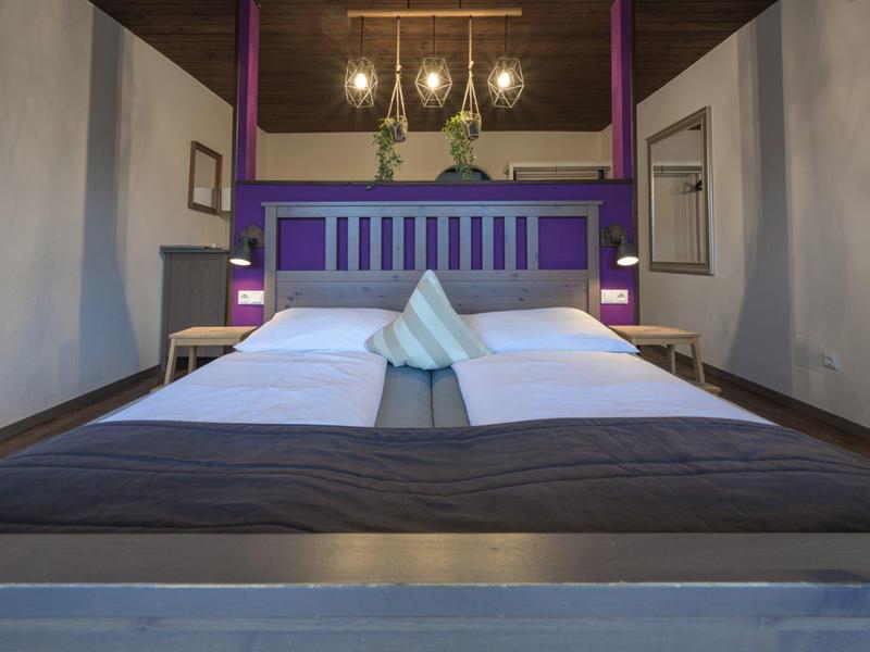 Modern eingerichtetes Hotelzimmer mit Doppelbett und stilvollen Lampen an der Wand.