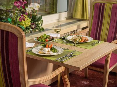 Zwei gedeckte Teller mit Essen auf einem Holztisch zwischen zwei gestreiften Stühlen in einem Hotelzimmer.