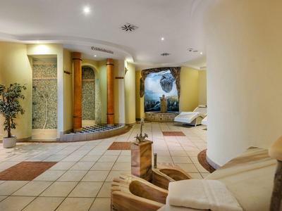 Moderner Hotel-Lobbybereich mit hellen Fliesen, Sitzmöbeln und künstlerischer Wanddekoration.