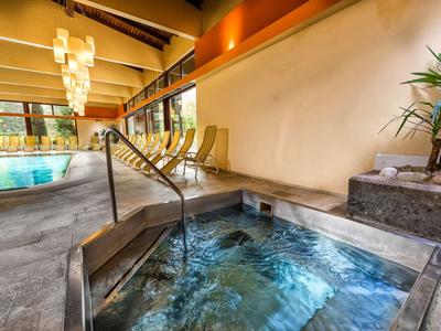 Innenbereich mit Whirlpool und Pool in einem Hotel mit moderner Beleuchtung und Sitzgelegenheiten.