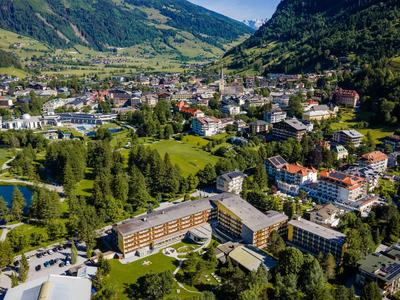 Bergdorf mit Hotels und Seen, umgeben von grünen Wäldern und hohen Bergen.