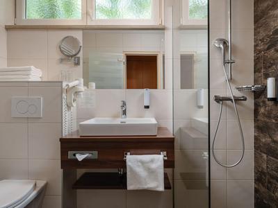 Modernes Hotelbadezimmer mit Waschbecken, Dusche und Toilette in neutralen Farben.