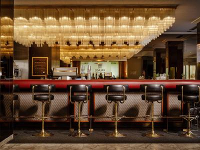 Elegante Bar mit fünf Drehhockern und warmen Deckenlichtern in einem Hotel.