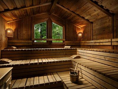 Holzsauna mit gestuften Sitzbänken und sanfter Beleuchtung unter einem schrägen Holzdeckendach.