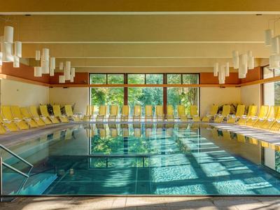 Innenpool mit großen Fenstern, gelben Liegestühlen und Holzverkleidung in einem Hotel.