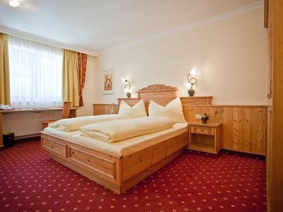 Gemütliches Hotelzimmer mit Doppelbett, Holzvertäfelung und rotem Teppichboden.