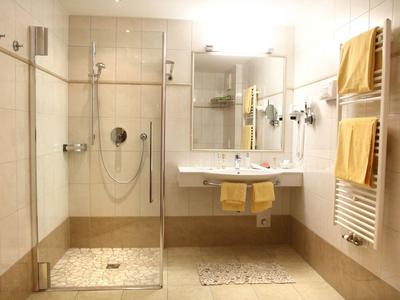 Modernes Hotelbad mit begehbarer Dusche, Doppelwaschbecken und gelben Handtüchern.