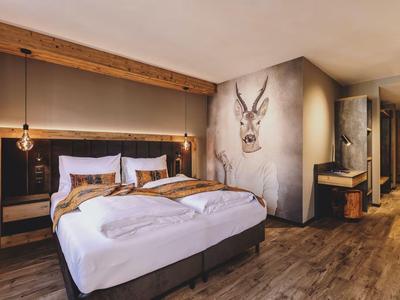 Modern eingerichtetes Hotelzimmer mit Doppelbett, Holzboden und dekorativer Hirschkopf-Wandkunst.