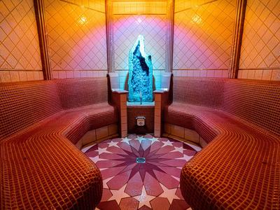 Gemütlicher Salon mit runden roten Sitzbänken, kleinem Tisch und dekorativer Statue an der Wand.