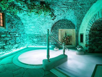 Beleuchtetes Spa-Bad in steinerner, archtiektonischer Umgebung eines Hotels mit Pflanzen.