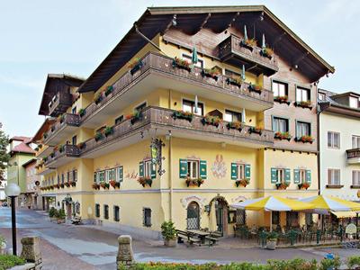 Gelbes Hotelgebäude mit Balkonen und Terrasse in einem ruhigen Straßenbereich.