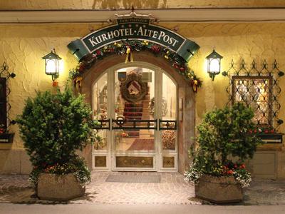 Eingang eines Hotels mit dekorativem Bogen, zwei großen Pflanzkübeln und Laternen.