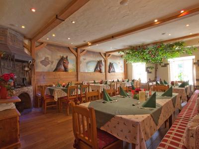 Gemütliches Restaurant mit Holzmöbeln, langen Tischen und gedeckten Plätzen unter einem Blätterdach.