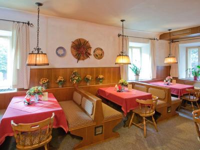 Gemütlicher Hotel-Speisesaal mit Holzmöbeln, roten Tischdecken und Blumenarrangements.