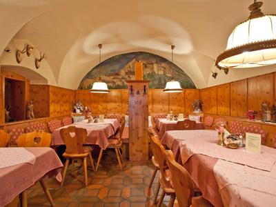 Gemütliches Restaurant mit Holzmöbeln und rosa gedeckten Tischen in gewölbtem Raum.