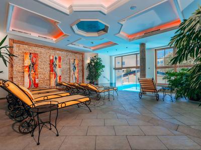 Helles Hallenbad mit Liegen, grünen Pflanzen und moderner Decke in einem Hotel.