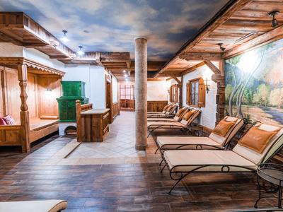 Heller Wellnessbereich mit Holzdetails, gemütlichen Liegen und Wandmalerei unter einem Himmelshimmel.