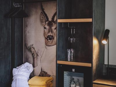 Moderne Hotellobby mit rauchgrauen Wänden, Regalen, Lampen und dekorativem Hirschbild an der Wand.