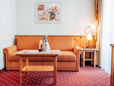 Gemütliche Hotelzimmerecke mit orangem Sofa, Holztisch und warmem Teppich.