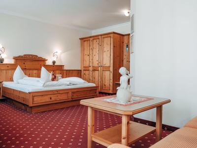 Gemütlich eingerichtetes Hotelzimmer mit Doppelbett, Holzschrank und Teppichboden.