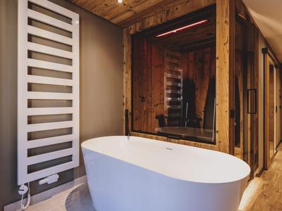 Moderne Badewanne vor Holzwänden in stilvollem Wellnessbereich eines Hotels.