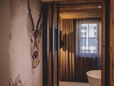 Badezimmer mit Holzwänden, freistehender Badewanne und Hirschkopf-Wanddekoration.