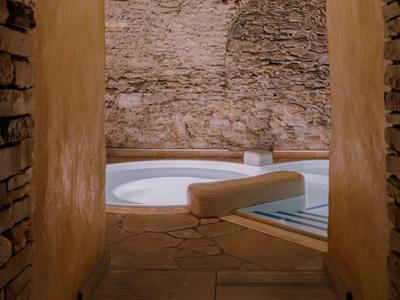 Gemütliches Spa mit Pool in warmem, rustikalem Steinumfeld für entspannte Hotelgäste.