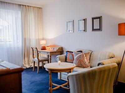 Gemütliches Hotelzimmer mit Sesseln, Sofa, Tisch und warmem Licht.