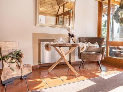 Gemütlicher Sitzbereich mit Teppich, Stuhl, kleinem runden Holztisch und Pflanzen.
