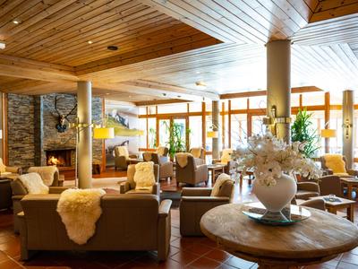 Gemütlicher Hotel-Loungebereich mit Holzmöbeln, Kamin und viel natürlichem Licht.