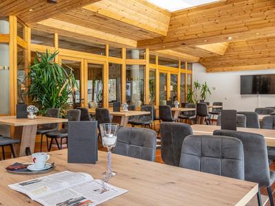 Helles Hotelrestaurant mit Holzmöbeln, gedeckten Tischen und moderner Einrichtung.