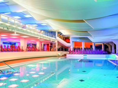 Moderner Innenpool mit Sitzbereich in einem Hotel bei warmem, farbigem Licht.