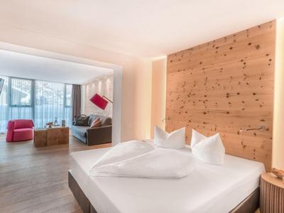 Camera d'hotel moderna con letto grande, dettagli in legno e zona soggiorno vicino alla finestra.