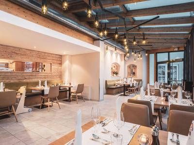 Ristorante luminoso e moderno con grandi finestre e tavoli apparecchiati.