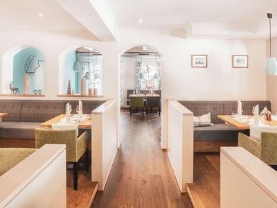 Ristorante luminoso con pavimento in legno, panche imbottite e tavoli, adatto agli ospiti dell'hotel.