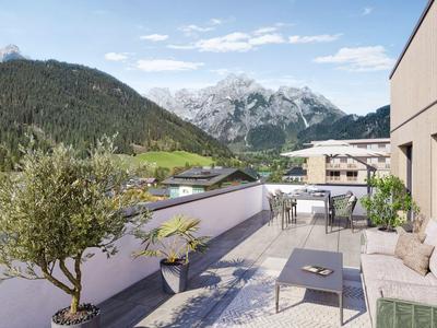 Terrazza dell'hotel moderna con area salotto e vista sulle montagne sotto un cielo azzurro.